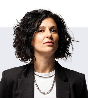 Donna con capelli ricci scuri, giacca nera e maglietta bianca